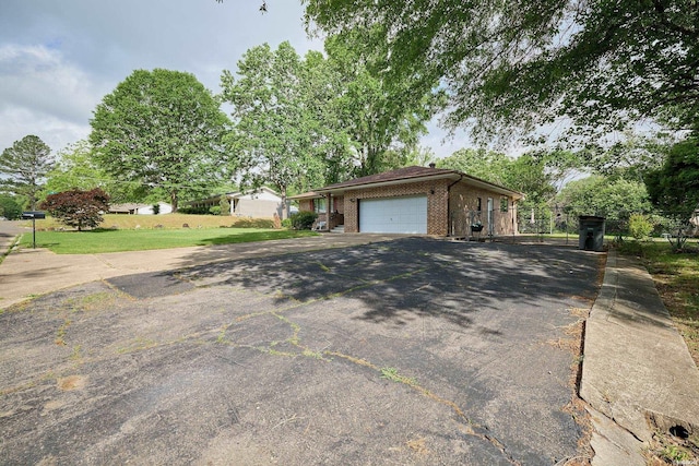 exterior space featuring aphalt driveway, fence, a garage, and brick siding