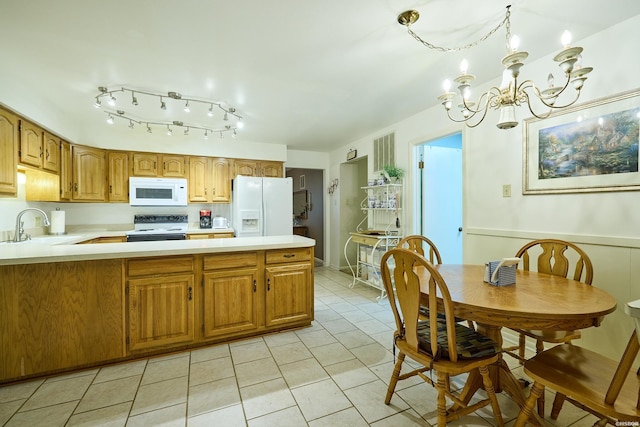 kitchen featuring light tile patterned floors, a sink, white appliances, light countertops, and a chandelier
