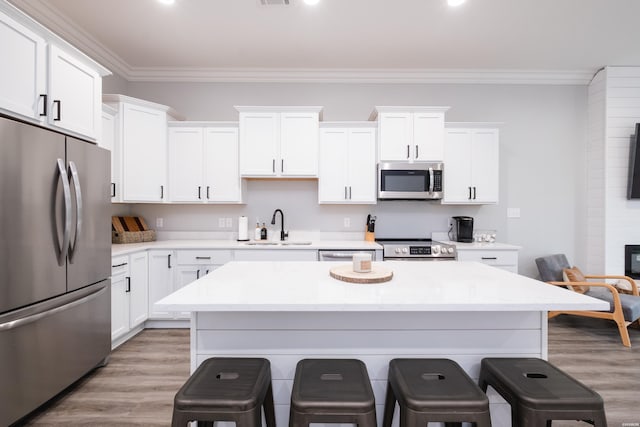 kitchen featuring a breakfast bar, light wood-style floors, appliances with stainless steel finishes, a sink, and a center island