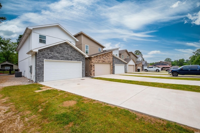 view of front of home featuring concrete driveway, stone siding, a front yard, an attached garage, and central AC
