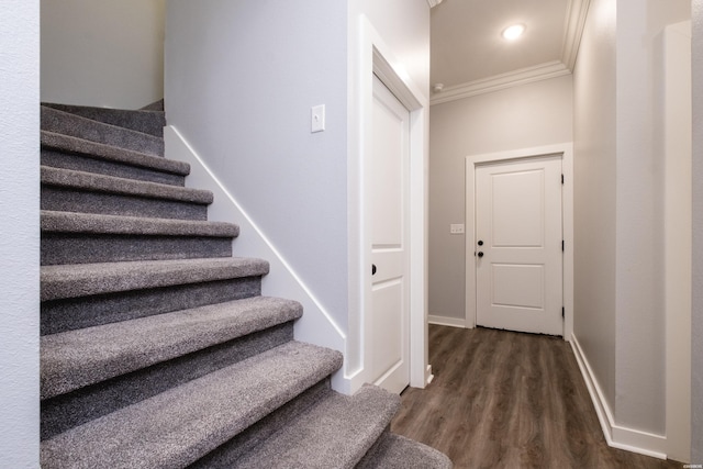 stairway featuring baseboards, ornamental molding, and wood finished floors