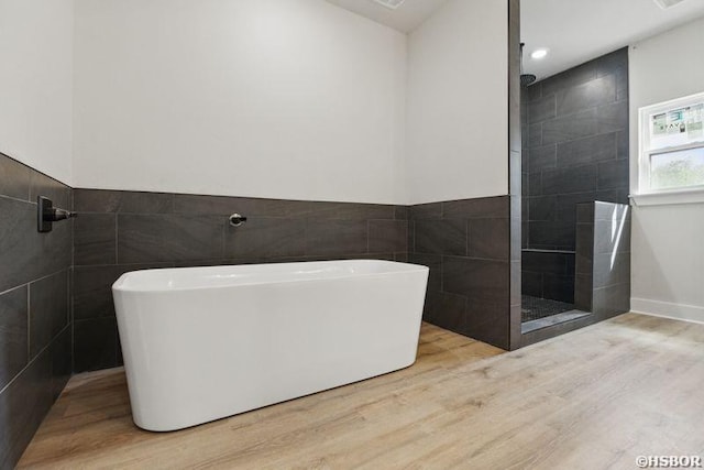 132 Lombard Ct, Hot Springs, AR 71901 - full bathroom featuring a wainscoted wall, a walk in shower, a freestanding bath, tile walls, and wood finished floors