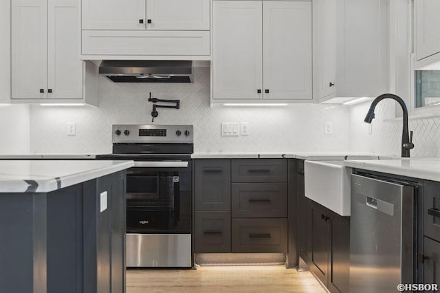 132 Lombard Ct, Hot Springs, AR 71901 - kitchen featuring appliances with stainless steel finishes, under cabinet range hood, a sink, light wood finished floors, and backsplash