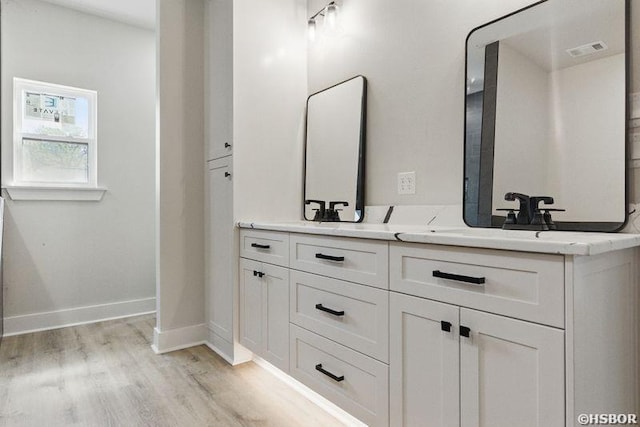 132 Lombard Ct, Hot Springs, AR 71901 - bathroom featuring visible vents, baseboards, a sink, double vanity, and wood finished floors