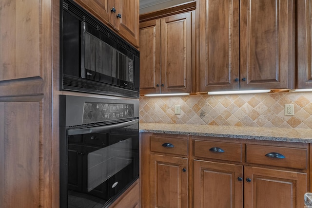 kitchen featuring light stone counters, backsplash, black appliances, and brown cabinetry