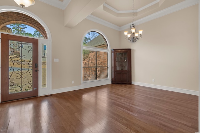 entryway featuring hardwood / wood-style floors, crown molding, a notable chandelier, and baseboards