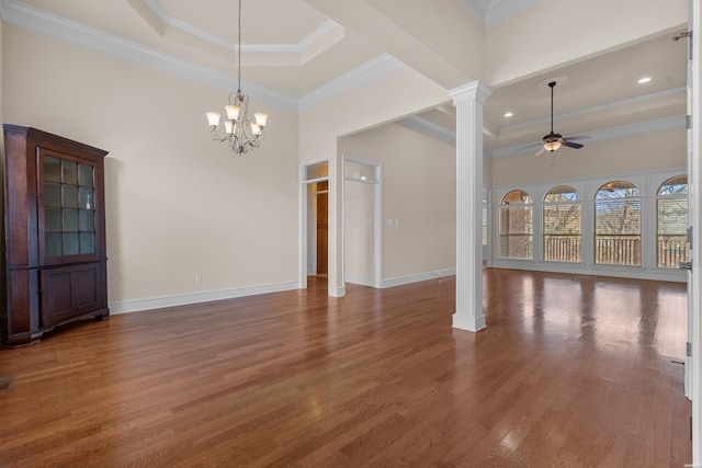 interior space with ceiling fan with notable chandelier, a tray ceiling, wood finished floors, and ornate columns