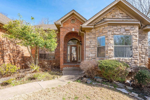 view of exterior entry featuring stone siding and brick siding