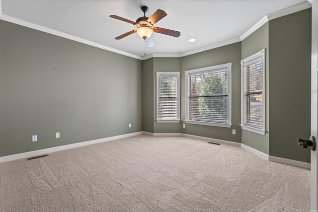 carpeted empty room featuring ceiling fan, baseboards, visible vents, and ornamental molding