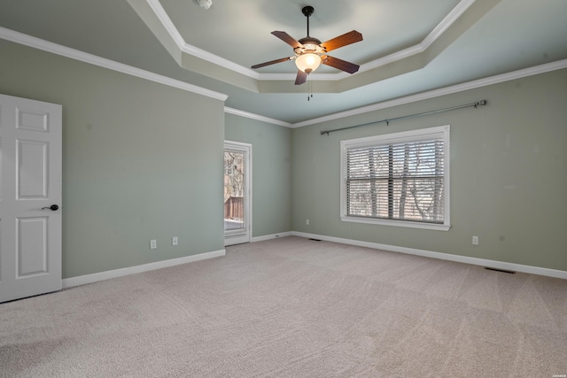 spare room featuring ornamental molding, a ceiling fan, a tray ceiling, carpet, and baseboards