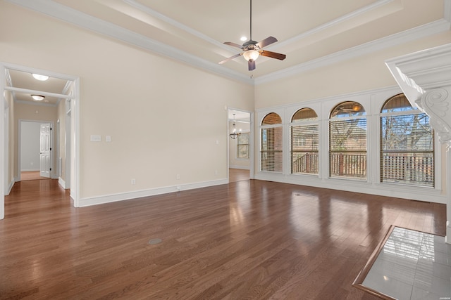 unfurnished room featuring wood finished floors, baseboards, crown molding, a raised ceiling, and ceiling fan with notable chandelier