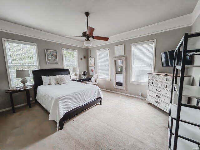 carpeted bedroom with a ceiling fan, baseboards, and crown molding