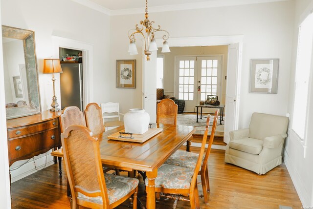 dining space featuring ornamental molding, french doors, a notable chandelier, and wood finished floors