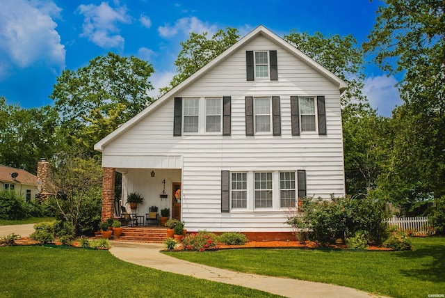 back of property featuring covered porch and a yard