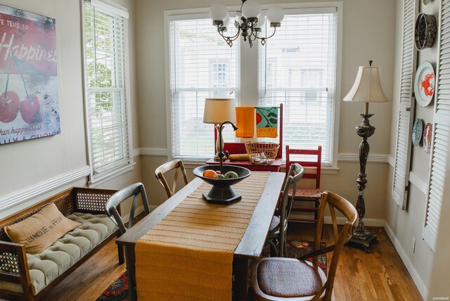 dining room with plenty of natural light, wood finished floors, and a notable chandelier