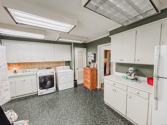 washroom featuring dark floors, separate washer and dryer, a sink, ornamental molding, and cabinet space