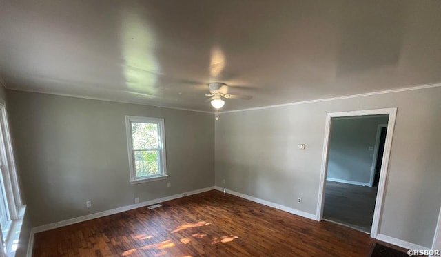 empty room featuring ceiling fan, visible vents, baseboards, dark wood-style floors, and crown molding