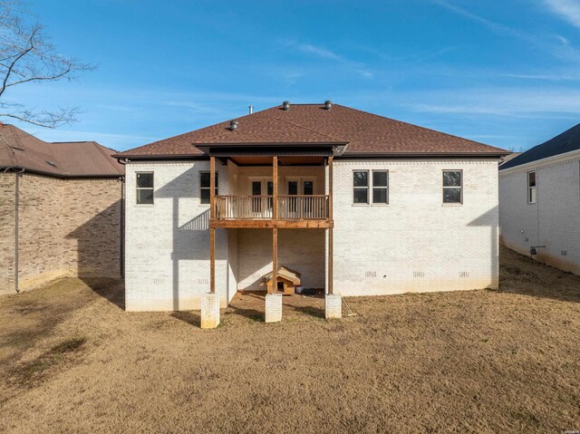 rear view of property featuring crawl space, a yard, roof with shingles, and brick siding