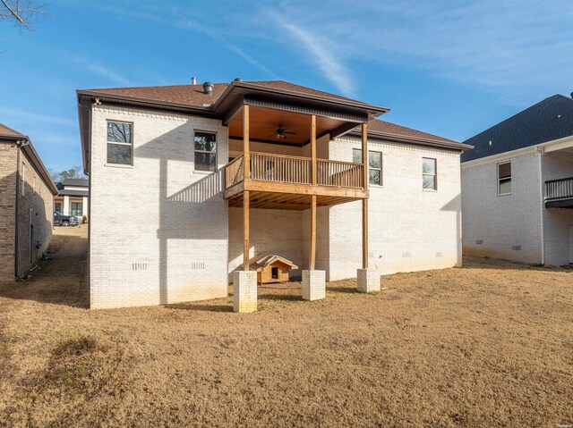 back of house with brick siding, a lawn, a balcony, and a ceiling fan