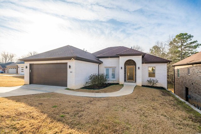 view of front of house featuring a garage, driveway, a front lawn, and brick siding