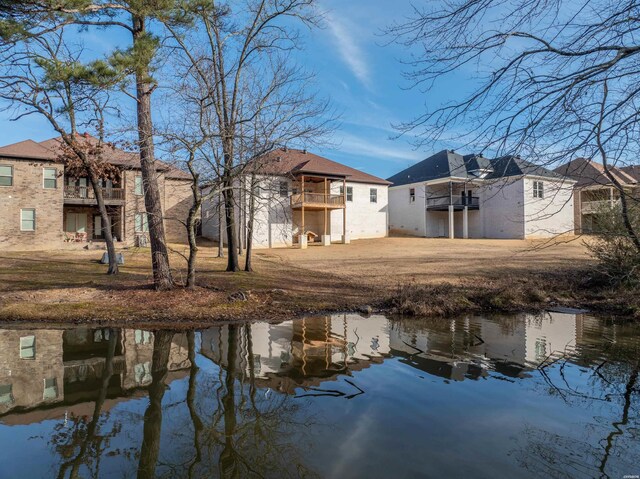 back of property with a water view and a balcony