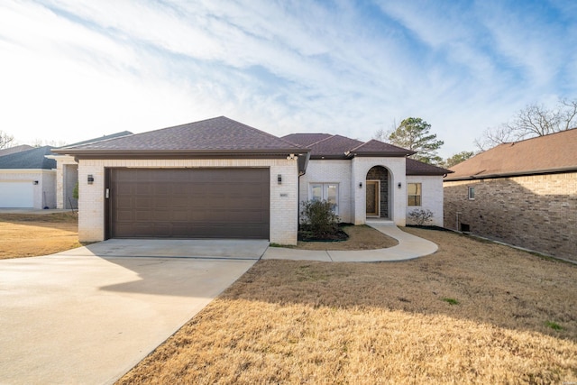 view of front of house with a garage, concrete driveway, roof with shingles, a front lawn, and brick siding