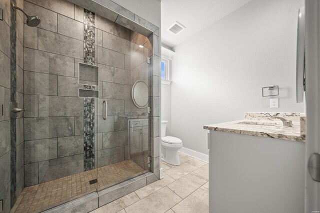 bathroom featuring toilet, a shower stall, vanity, and tile patterned floors