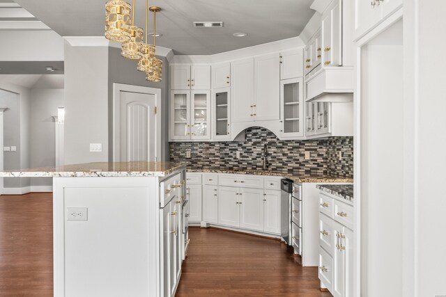 kitchen with white cabinets, a kitchen island, glass insert cabinets, and pendant lighting