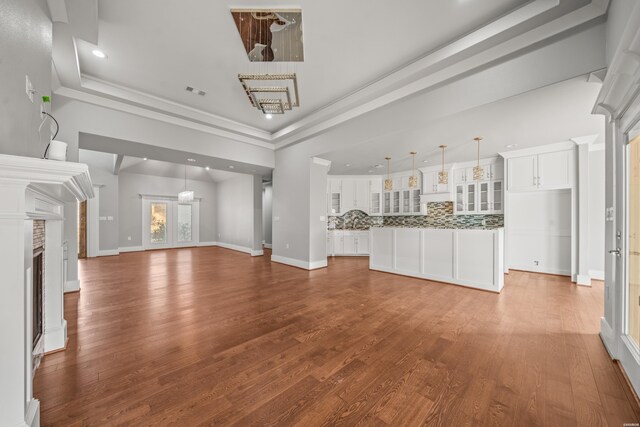 unfurnished living room with a fireplace, a tray ceiling, and wood finished floors