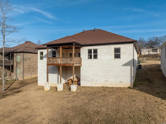 back of property featuring a shingled roof, a balcony, crawl space, a yard, and brick siding