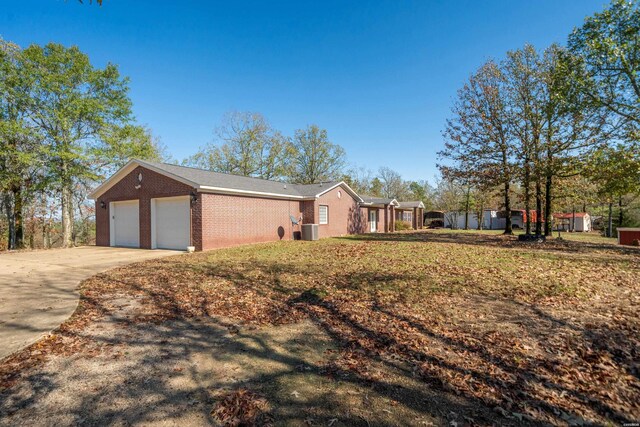 view of front of house featuring a garage, driveway, brick siding, and central AC