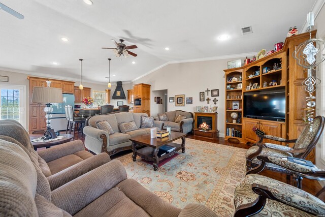 living room featuring lofted ceiling, visible vents, wood finished floors, and ornamental molding