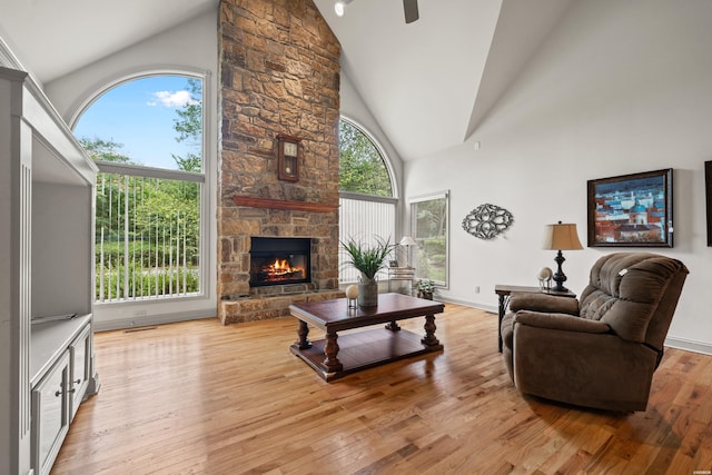 living area with high vaulted ceiling, a fireplace, light wood-style flooring, and baseboards