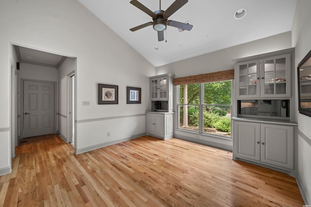 interior space featuring baseboards, high vaulted ceiling, a ceiling fan, and light wood-style floors