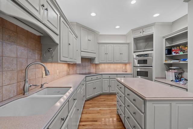 kitchen featuring light countertops, stainless steel double oven, a sink, and black electric cooktop