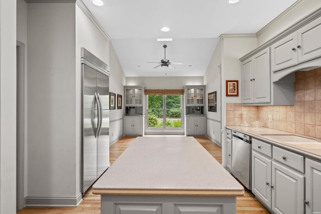 kitchen with appliances with stainless steel finishes, a center island, light countertops, and gray cabinetry