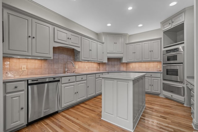 kitchen featuring gray cabinetry, stainless steel appliances, a sink, a kitchen island, and light countertops