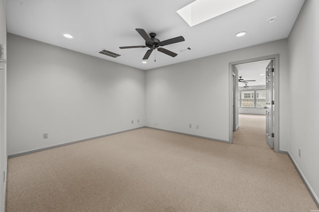 spare room with a skylight, recessed lighting, light colored carpet, visible vents, and baseboards