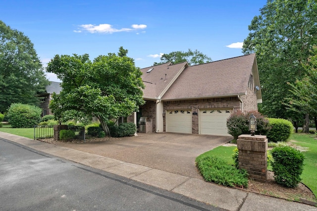 view of front of house with an attached garage, brick siding, fence, driveway, and roof with shingles