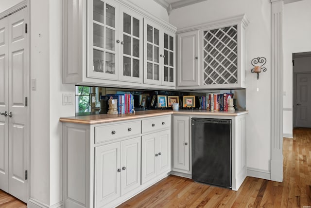 kitchen with light wood-type flooring, fridge, glass insert cabinets, and white cabinets