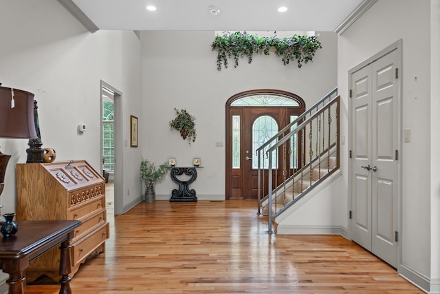 foyer entrance with plenty of natural light, light wood-type flooring, and stairs