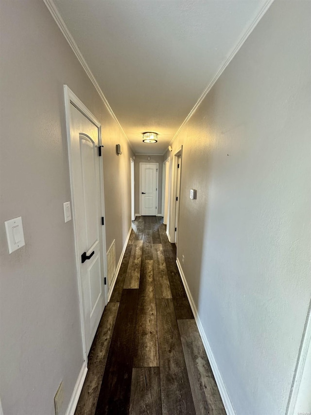 hallway featuring baseboards, ornamental molding, and dark wood-style flooring