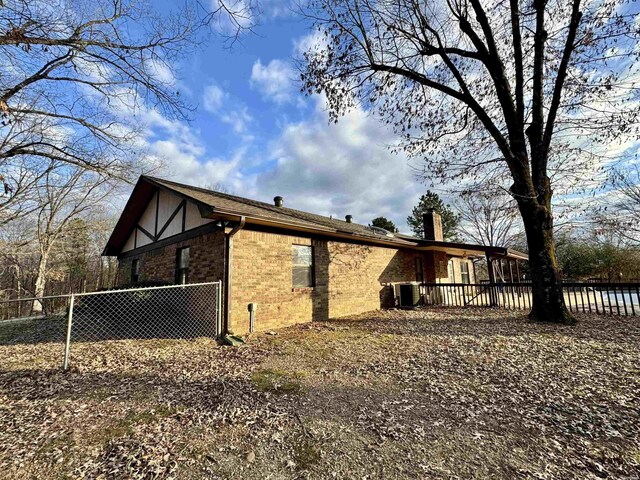 view of home's exterior featuring a chimney, fence, and brick siding