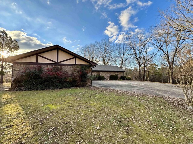 view of front facade featuring driveway, a front lawn, and brick siding