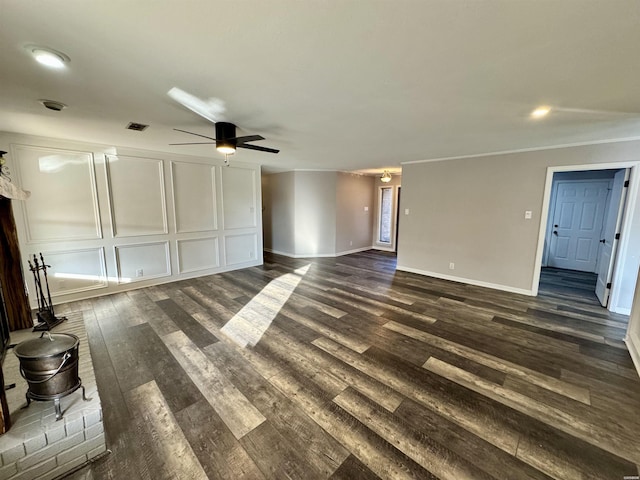 unfurnished living room featuring ceiling fan, baseboards, a decorative wall, and dark wood-type flooring