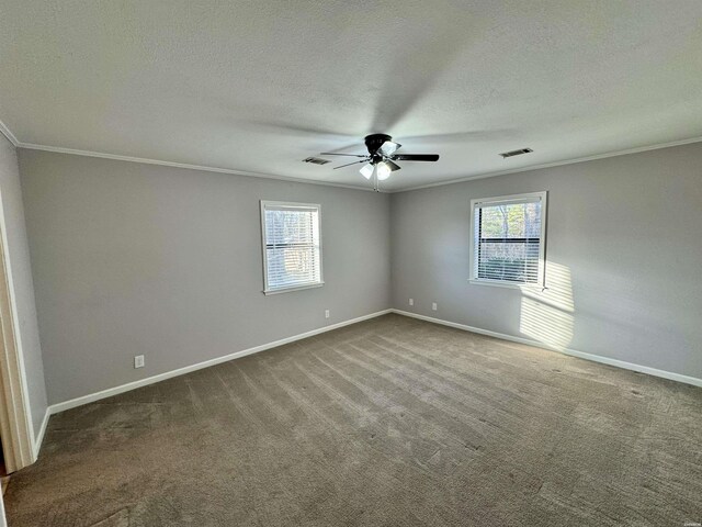 empty room with carpet, a healthy amount of sunlight, crown molding, and baseboards