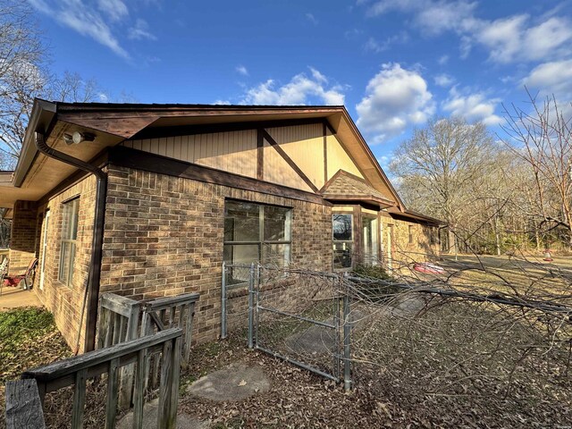 view of side of property featuring fence and brick siding