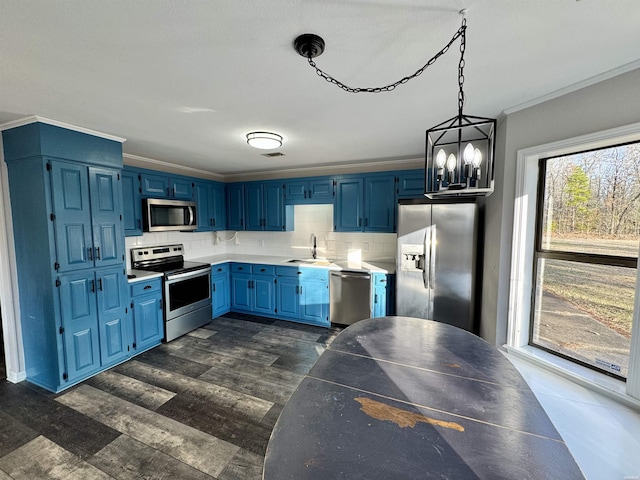 kitchen with crown molding, blue cabinetry, hanging light fixtures, appliances with stainless steel finishes, and a sink