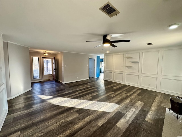 unfurnished living room with a decorative wall, visible vents, dark wood finished floors, and ornamental molding