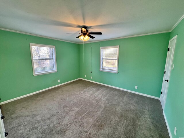 empty room with dark colored carpet, ornamental molding, plenty of natural light, and baseboards